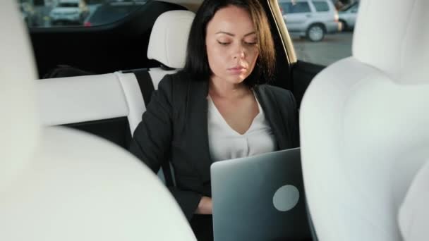年轻的女士坐在车后座上 在笔记本电脑上打字 上网工作 商业概念 慢动作 — 图库视频影像