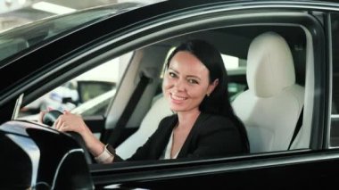 Şehirde araba sürmeye gitmeden önce sürücü koltuğunda oturan mutlu genç bayan. Ulaşım, seyahat, yaşam tarzı konsepti. Yavaş çekim