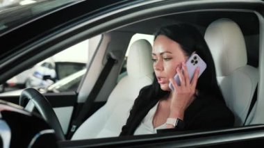 Şoför koltuğunda otururken akıllı telefondan konuşan sakin genç bayan. Ulaşım, teknoloji, gezi, iş konsepti. Yavaş çekim