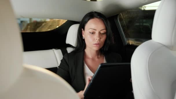 漂亮的女士坐在出租车后座上 一边上网一边用数码平板电脑 商业概念 慢动作 — 图库视频影像