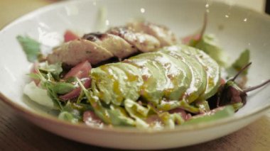 Avokado, sebze ve beyaz tabakta balzamik soslu tavuk eti ile sağlıklı salata. Kapatın. Sağlıklı yemek, keto diyeti konsepti. Yavaş çekim