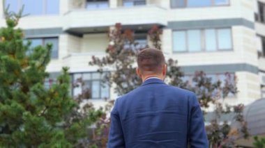 Dikiz aynası. Kamera, takım elbiseli, mutlu ve kendine güvenen genç bir adama yaklaşıyor. Dışarıda kameraya dönüyor ve gülümsüyor. Sokakta poz veren Kafkasyalı bir işadamı. İş konsepti, şehir, kapat