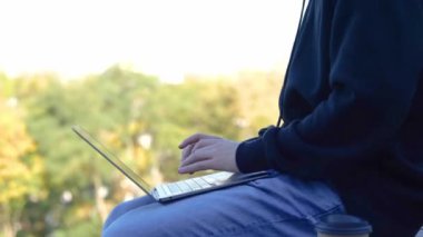 Diz üstü bilgisayarla çalışan ve şehir parkındaki bankta oturan meşgul bir erkek. Yan görüş. Uzayı kopyala Sonbahar sezonu. Eğitim, çalışma konsepti. Gerçek zamanlı konsept.