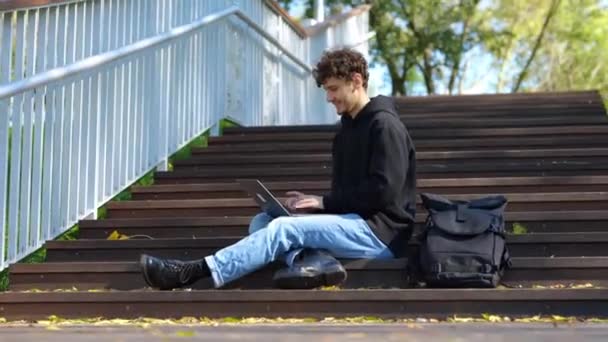 Uśmiechnięty Stylowy Facet Piszący Laptopie Siedząc Schodach Parku Jesienny Sezon — Wideo stockowe