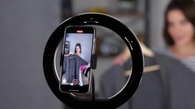 Cep telefonuyla kameraya gri süveteri gösterirken evde canlı viral video kaydedecek kadar mutlu. Küçük işletme, çevrimiçi pazar konsepti. Gerçek zamanlı video.