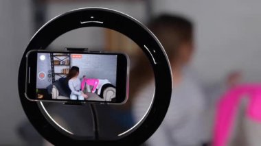 Gülümseyen beyaz blogcu kadın kameraya kıyafetlerini gösterip bir gün için bakmayı seçiyor. Kadın cep telefonuyla video kaydediyor. Gerçek zamanlı video.
