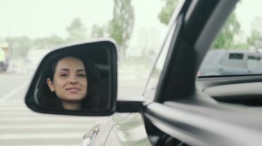 Arabada dikiz aynasına bakan mutlu genç bayan. Güvenli sürüş, ulaşım, seyahat konsepti. Yavaş çekim