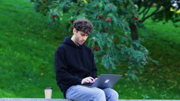 Guy Arbeitet Mit Laptop Und Tippt Während Stadtpark Sitzt Und — Stockvideo