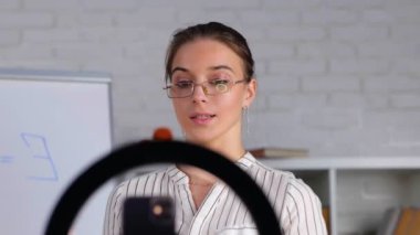 Kafkasyalı bayan öğretmen, arka planda parmak izi çizelgesi olan cep telefonuyla matematik öğretiyor. Uzaktan kumandalı sınıf. - Evet. Gerçek zamanlı video.
