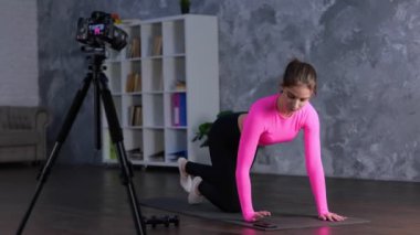 Sportif kadın evde kalas egzersizi yapıyor. Genç bayan telefon ekranına dokunarak spor minderi kullanarak kas çalıştırıyor. Spor, spor, aerobik, sağlık konsepti. Gerçek zamanlı video.