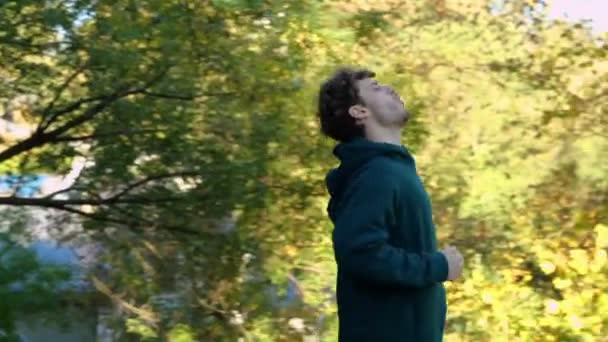 夏の晴れた日に公園で走っている若い白人男性 アウトドア活動 背中に痛みを感じている リアルタイム 緑の木の間で森林で走るスポーツマン トレーニング後に腰痛を感じる — ストック動画