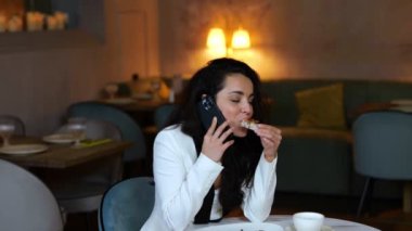 Konuşurken ve restoranda yemek yerken akıllı telefonu tutan gülümseyen çekici kadın. Uzayı kopyala İş, yaşam tarzı konsepti. Gerçek zamanlı video.