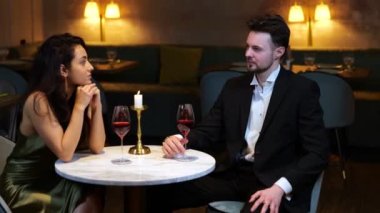 Modern bir restoranda oturup şaraptan zevk alan mutlu bir adam ve kadın. Yaşam tarzı, aşk, ilişkiler. Gerçek zamanlı video.