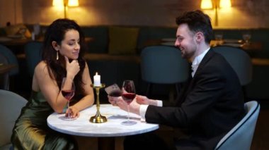 Gülümseyen adam restoranda romantik bir akşam yemeğinde cep telefonu kullanıyor ve kadınlara gösteriş yapıyor. Yaşam tarzı, aşk, ilişkiler. Gerçek zamanlı video.