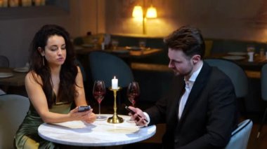Restoranda erkek arkadaşına gösterirken cep telefonu tutan güzel bir kadın. Yaşam tarzı, aşk, ilişkiler. Gerçek zamanlı video.
