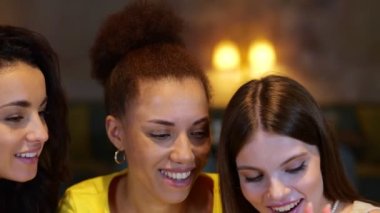 İnternette cep telefonuyla konuşurken restoranda oturmuş gülümseyen güzel bayan arkadaşlar. Arkadaşlarla buluşacağız. Yaşam tarzı, arkadaşlık kavramı. Gerçek zamanlı video.