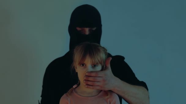 男人捂住受惊小孩的嘴穿着黑色巴拉克拉瓦的绑架者偷走了小女孩 绑架儿童的概念 实时视频 — 图库视频影像