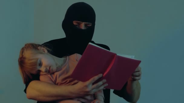 男性绑架者在为小女孩人质看书时 小女孩睡在罪犯的手里 复制空间 绑架儿童的概念 实时视频 — 图库视频影像