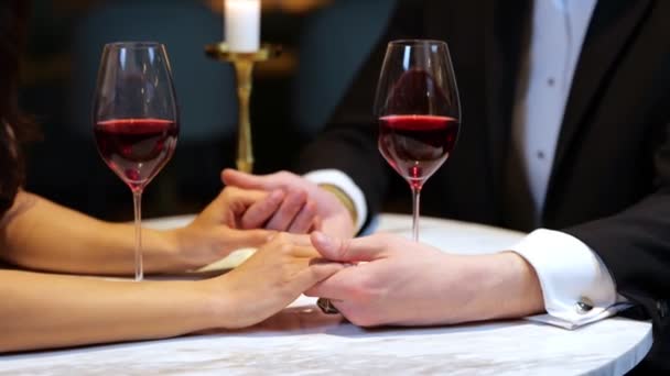 Man holding female hands while having romantic date in the restaurant, cropped, close up. Lifestyle, love, relationships concept. Real time video.