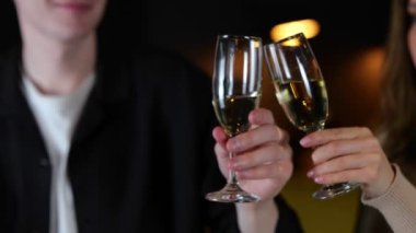 Genç bir adam ve kadın bir restoranda kutlama sırasında şampanya bardaklarını tokuşturuyorlar. Kapatın. Yaşam tarzı, ilişki, randevu konsepti. Gerçek zamanlı..