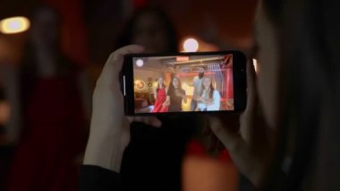 Kadın ellerindeki cep telefonu ekranını kapat. Arkadaşlarının gece kulübünde dans ettiğini videoya çeken bir kadın. Yaşam tarzı, dans, disko konsepti. Gerçek zamanlı..