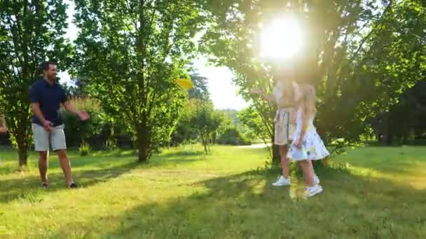 コカシアの家族は晴れた日に公園でフリスビーディスクを投げる 笑顔の女の子は ママとパパがフリスビープレートで遊んでいる間 両親のために応援をジャンプします 子供も親も楽しんでいる リアルタイム サマーアウトドア — ストック動画