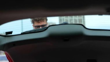 Tatile çıkmadan önce seyahat çantalarını geniş bir arabanın bagajına koyuyor. Seyahat, ulaşım, tatil, yaşam tarzı konsepti. Gerçek zamanlı.