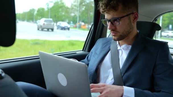 ラップトップとタイピングを使用して 車の後部座席に座っている間 正式な服の若い実業家 ビジネス 技術コンセプト リアルタイム — ストック動画
