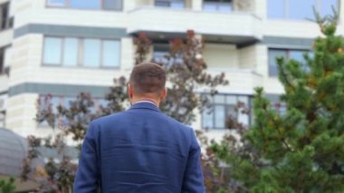 Dikiz aynası. Kamera, takım elbiseli, mutlu ve kendine güvenen genç bir adama yaklaşıyor. Dışarıda kameraya dönüyor ve gülümsüyor. Sokakta poz veren Kafkasyalı bir işadamı. İş konsepti, şehir, kapat