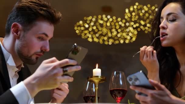 在餐厅吃饭的时候 男人和女人一边看手机屏幕一边吃沙拉 生活方式 关系的概念 实时视频 — 图库视频影像