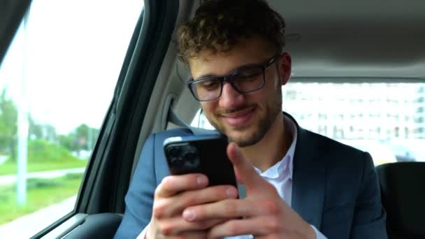 Счастливый Молодой Бизнесмен Печатает Сообщение Смартфоне Сидя Такси Концепция Бизнеса — стоковое видео