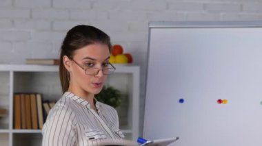 Elinde tablet tutarak tripoddaki akıllı telefon kamerasıyla matematik dersi veren genç beyaz bir öğretmen. Online eğitim. Gerçek zamanlı video.