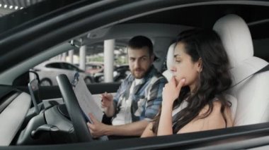 Erkek eğitmenle arabada otururken test sürüşü raporuna bakan hayal kırıklığına uğramış bir bayan. Sürüş testi, ulaşım konsepti. Yavaş çekim
