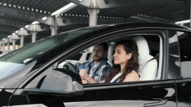 Gülümseyen genç bayan yola bakıyor ve erkek eğitmenle araba sürmek için ders çalışıyor. Sürüş testi, ulaşım konsepti. Yavaş çekim