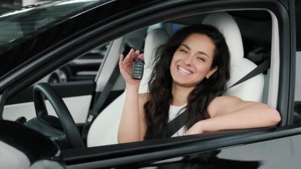 Smiling pretty lady showing key of new car while sitting on driver seat. Driving test, transport concept. Slow motion