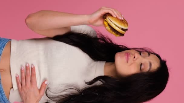 행복한 숙녀는 햄버거를 들고있는 배고프다 스튜디오에서 배경에 건강에 해로운 개념입니다 — 비디오