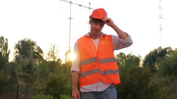 Uśmiechnięty Inżynier Zdejmujący Kask Bezpieczeństwa Stojący Pobliżu Linii Wysokiego Napięcia — Wideo stockowe