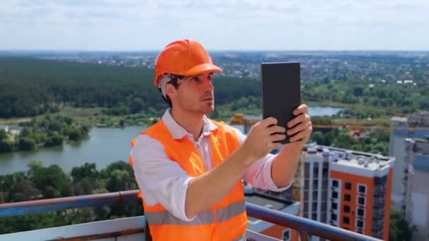 Erkek Ustabaşı Dijital Tablet Kullanarak Inşaat Alanının Videosunu Çekerken Çatıda — Stok video