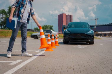 Ehliyet sınavı sırasında kız öğrenci trafik konisi tutarken sürücü kursunda. Test sürüşü, ulaşım, güvenlik, eğitim kavramı