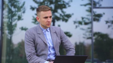 Genç adam dışarıda oturup yazarken dizüstü bilgisayarla çalışıyor. Uzayı kopyala İş, teknoloji kavramı. Yavaş çekim