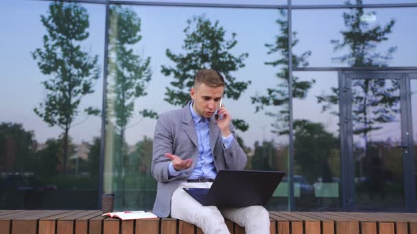 Jovem Empresário Usando Laptop Enquanto Fala Smartphone Trabalhando Livre Negócio — Vídeo de Stock