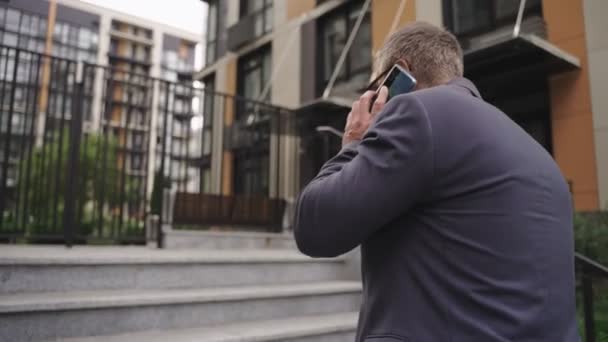大人のビジネスマンは 屋外の階段を上がっている間 携帯電話で話しています ビジネス コミュニケーション 技術コンセプト スローモーション — ストック動画