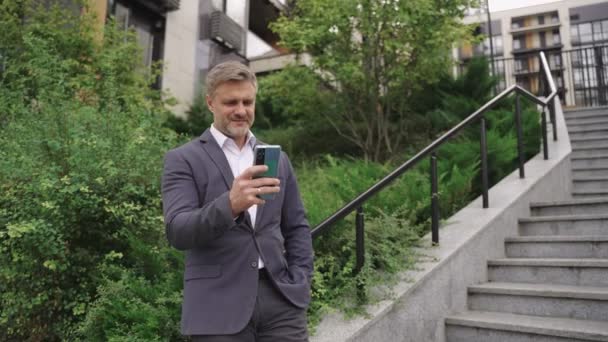 用智能手机微笑的商人 站在城市的台阶边 技术概念 慢动作 — 图库视频影像