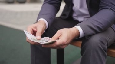 Para tutan bir işadamı, sayıyor, kentteki bankta oturuyor. İş, ödeme konsepti. Yavaş çekim