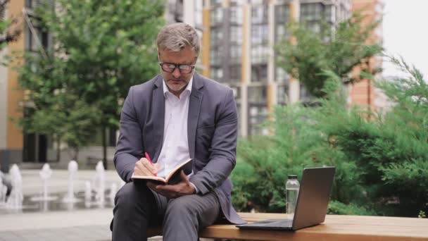 Businessman Making Notes Notebook Using Laptop Sitting Bench City Business — Stock Video
