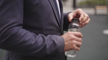 Elinde su şişesiyle caddede duran bir iş adamı. İş, insanların kavramı. Yavaş çekim