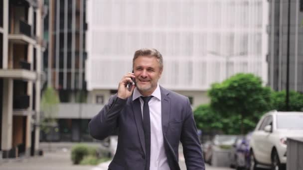 Happy Adult Businessman Holding Mobile Phone Talking While Walking City — Stock Video