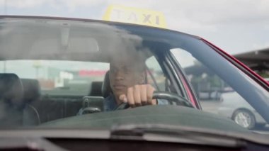 Sakin Afrikalı Amerikalı taksi şoförü şehirde arabasını sürüyor. Sarı taksi arabası tabelası. İnsanlar, iş, hizmet kavramı. Yavaş çekim