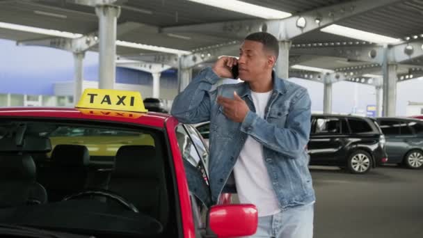 アフリカ系アメリカ人のタクシー運転手が赤い車に乗りながら携帯電話で話している 黄色いタクシー車の屋根サイン 技術コンセプト スローモーション — ストック動画