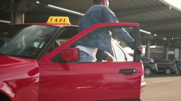 アフリカ系アメリカ人の若いタクシー運転手がバッグ付きの美しい女性のための車のドアを開けます ライフスタイル 旅行のコンセプト スローモーション — ストック動画
